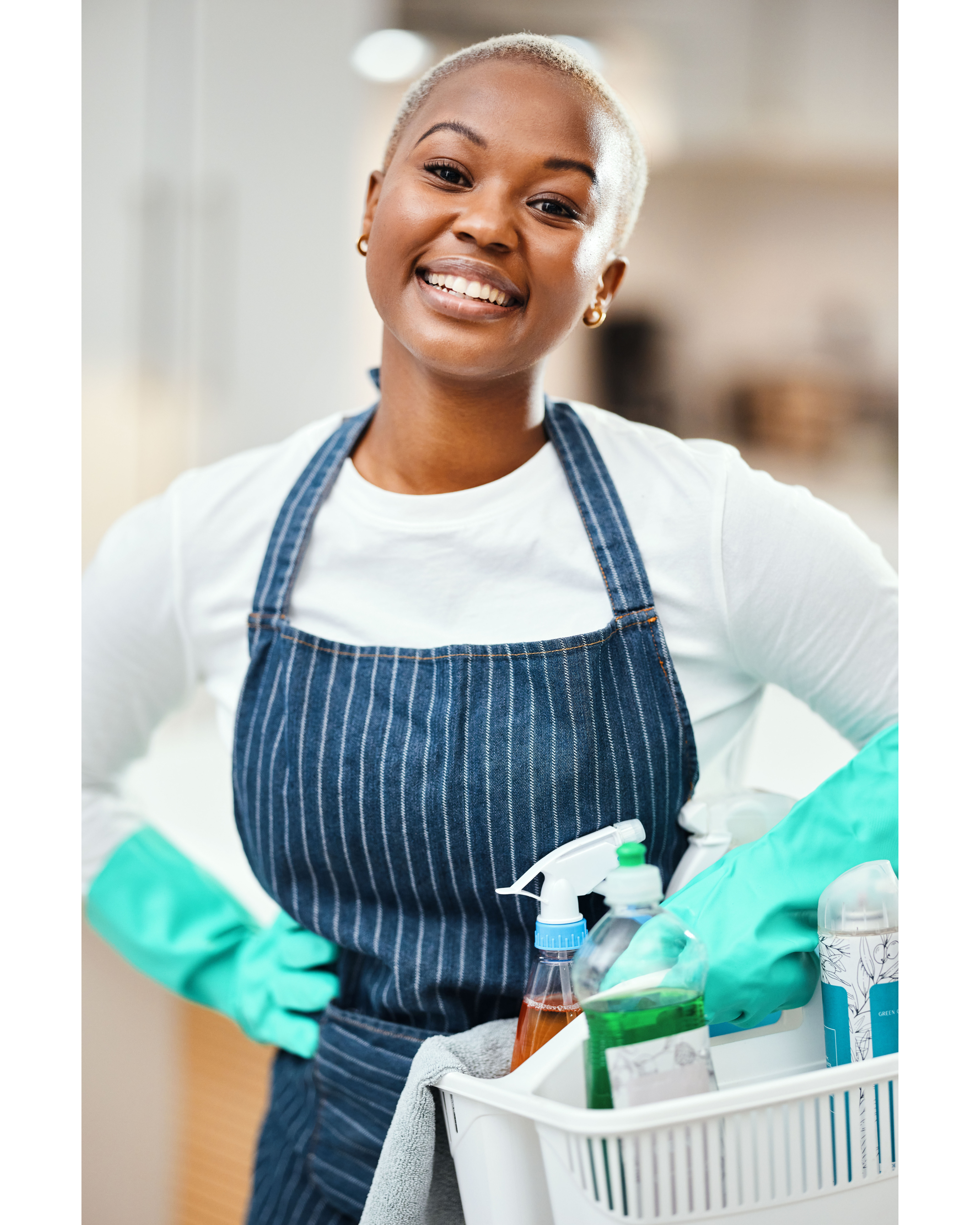 Woman smiling, while holding a cleaning caddy with spray bottles.